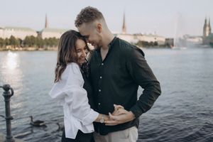 Happy couple embracing by the Alster Lake in Hamburg, Germany during a beautiful summer evening.